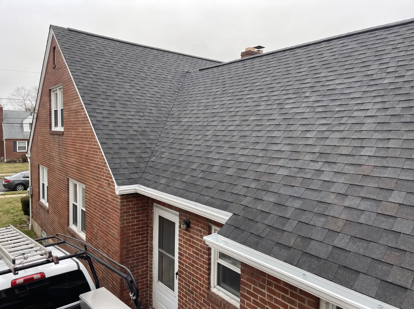 The same brick twin home with a new charcoal architectural shingle roof